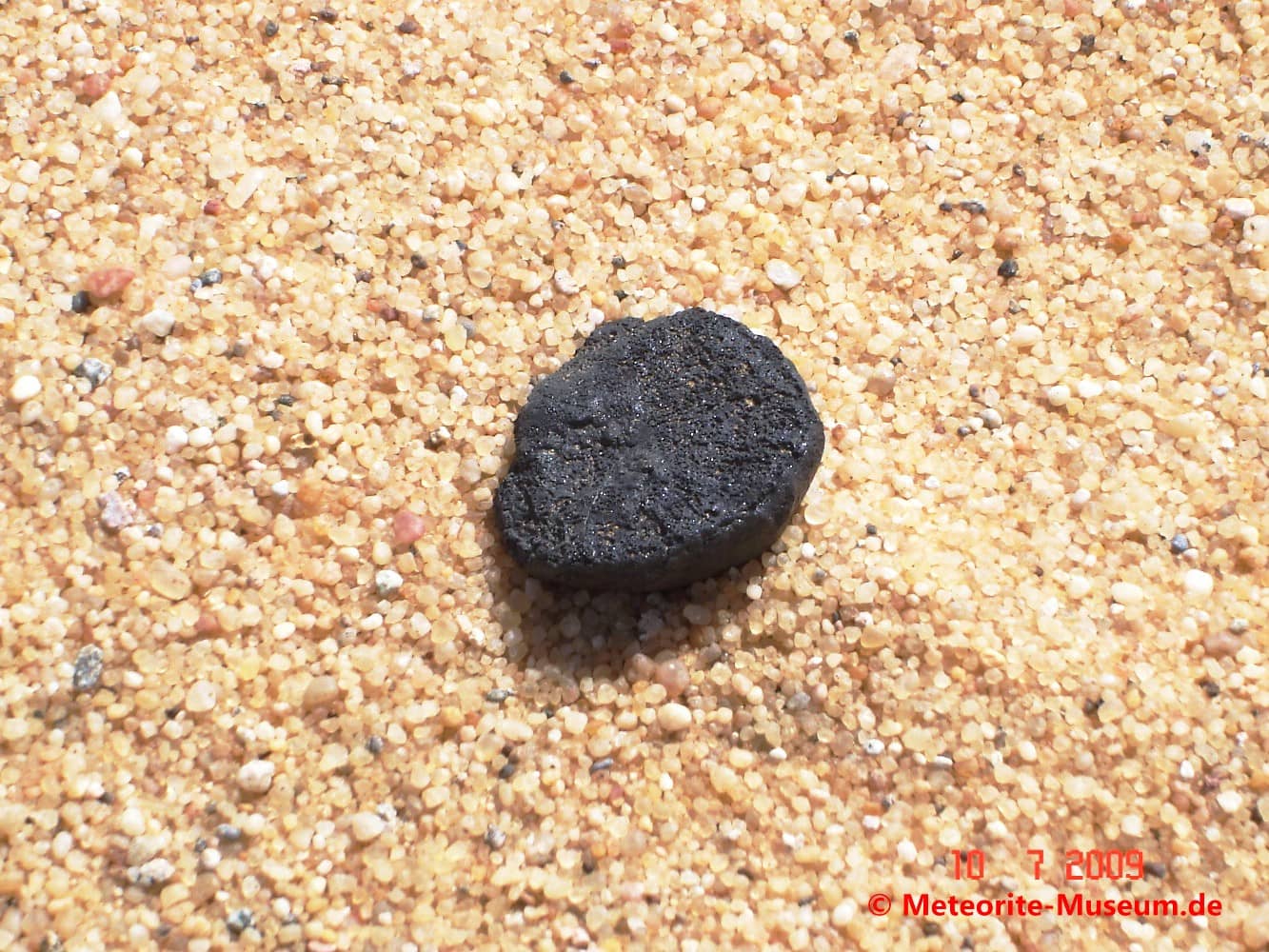 Almahata Sitta Meteorit Bruchstück auf dem körnigen Wüstensandboden