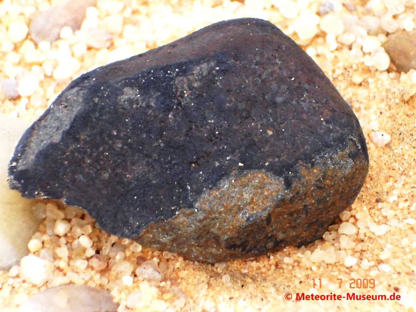 Nahaufnahme eines Almahata Sitta Bruchstück Meteorit mit teilweiser abgeplatzter und schwarzer Schmelzkruste