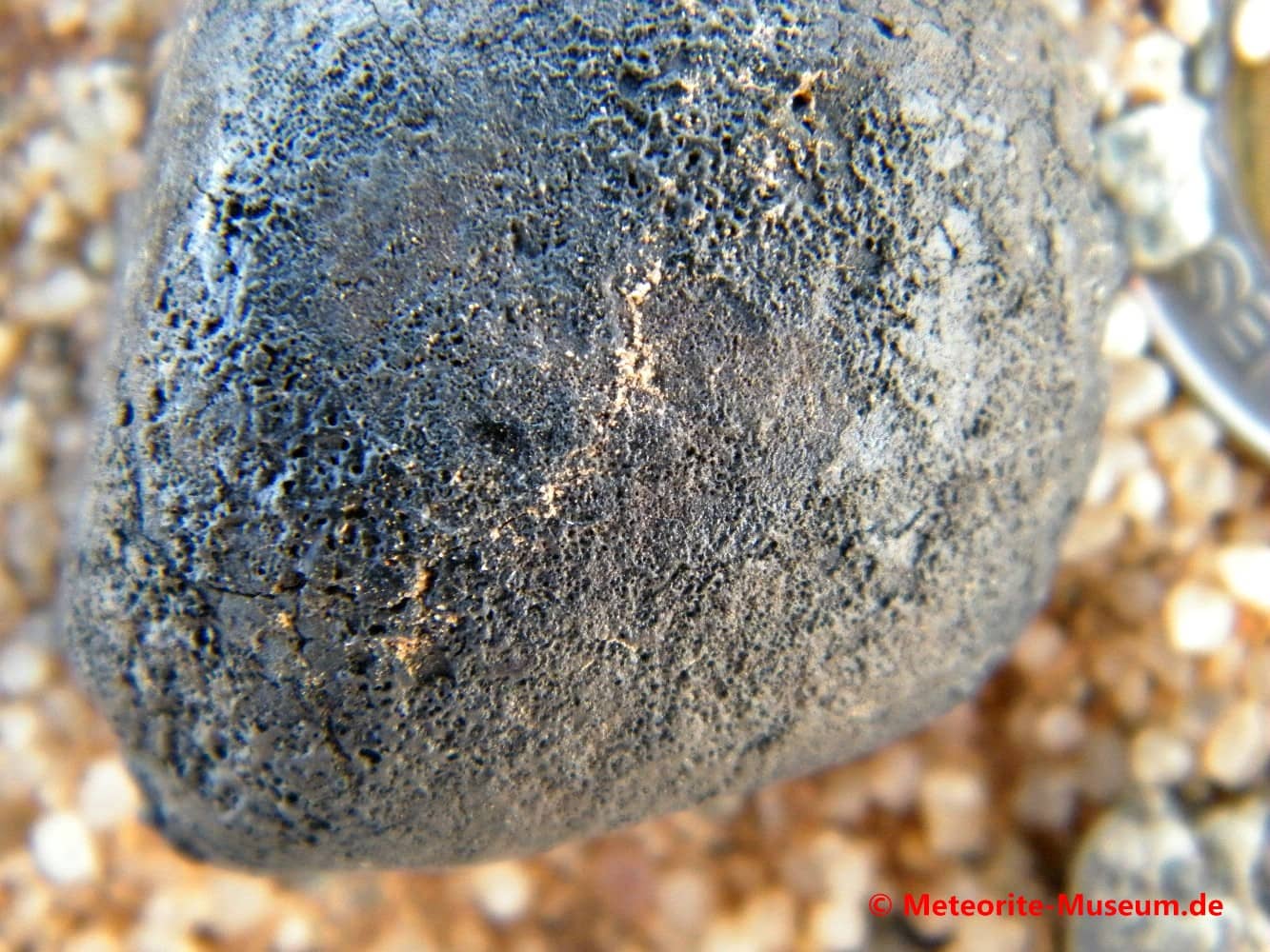 Nahaufnahme eines Almahata Sitta Individuum Meteorit mit frischer und schwarzer Schmelzkruste