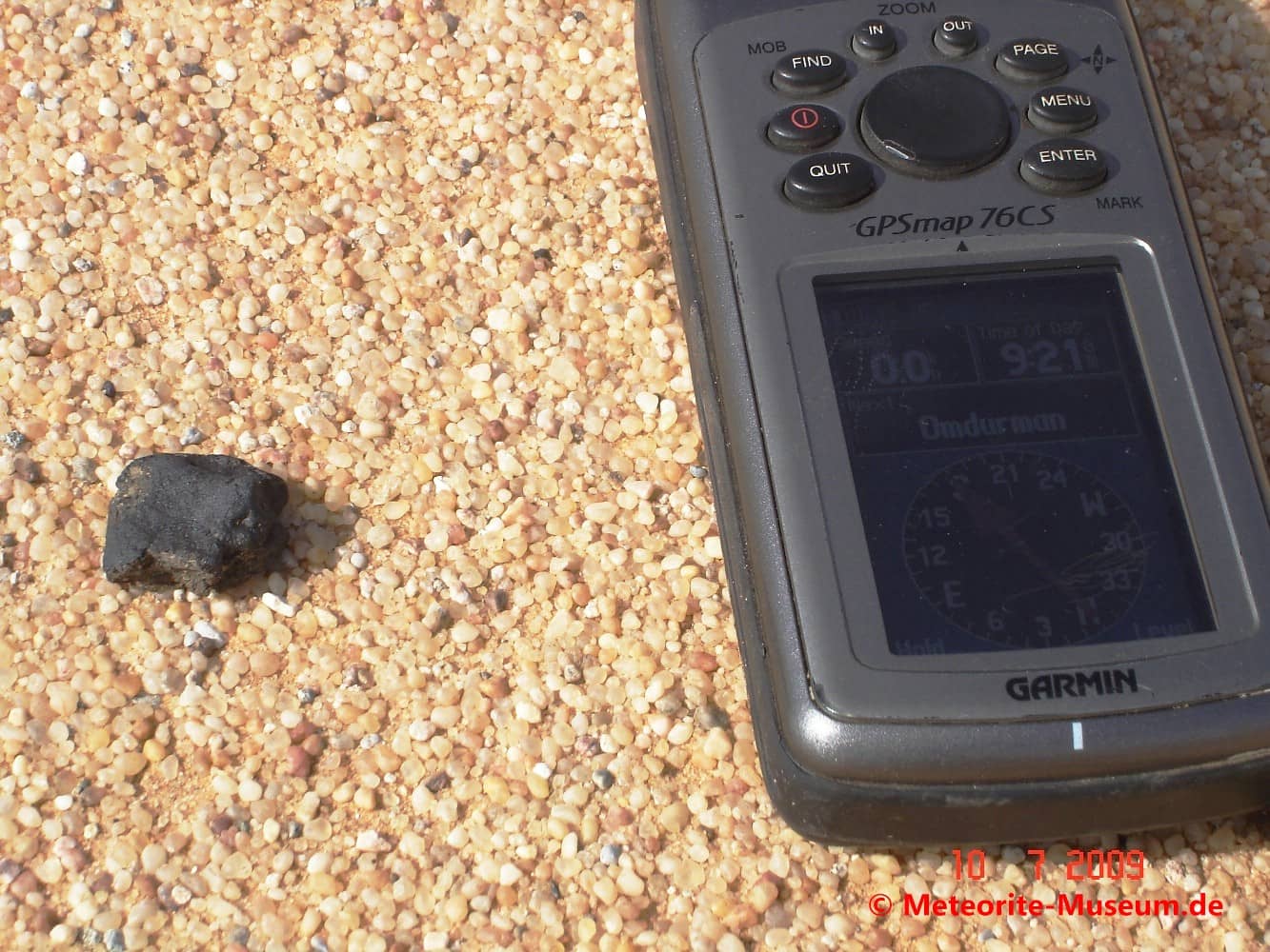 Almahata Sitta Meteorit neben GPS-Gerät auf dem Wüstensandboden zur Feststellung der Fund-Koordinaten